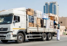 A stressed couple surrounded by cardboard boxes while talking to a mover in Dubai, illustrating the risks of hiring cheap movers in dubai and hidden costs during relocation.